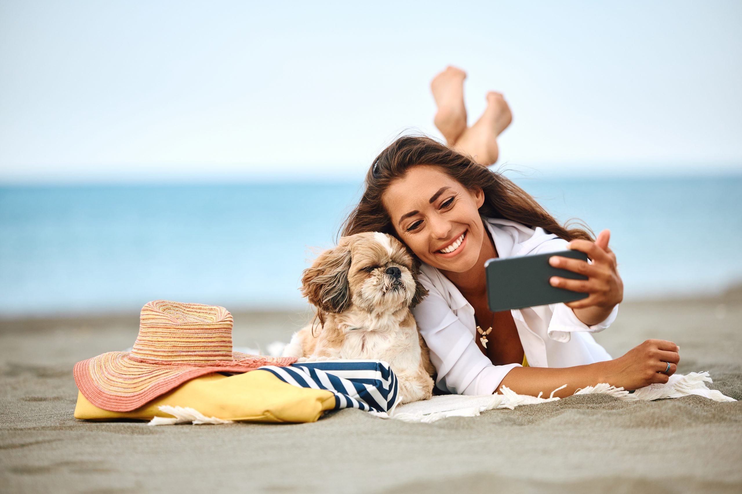 Mulher tirando foto com cachorro na praia